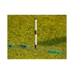 Ein schwarz-weißer Markierstab wurde mit einem weiteren kombiniert und steckt in einer grünen Wiese. Darum herum liegen mehrere grüne Dummybeutel.