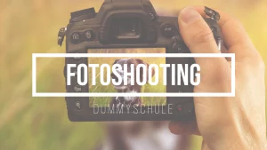 Beitragsbild zum Beitrag Fotoshooting mit Hund. Das Bild zeigt eine professionelle Kamera wird von einer Hand gehalten. Auf dem Bildschirm der Kamera sieht man ein Portrait von einem Hund, welches gerade geschossen wird. Der Hund sitzt im Hintergrund auf einer Wiese.